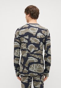 Camisa de manga longa com um padrão de camuflagem em tons de verde, cinza e azul-marinho, feita de um tecido leve e elástico.