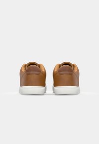 Bruine leren sneakers met witte rubberen zolen, afgeronde hak en gestroomlijnd ontwerp. Opvallende stiksels en gevoerde kraagdetails.