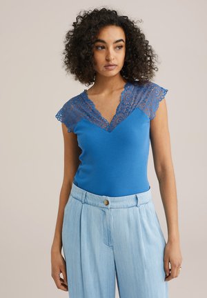 Top fără mâneci de culoare albastră, cu un guler din dantelă texturată. Prezintă un corp ajustat din material cu nervuri și un design cu decolteu în V. Asortat cu pantaloni largi de culoare albastră deschisă.