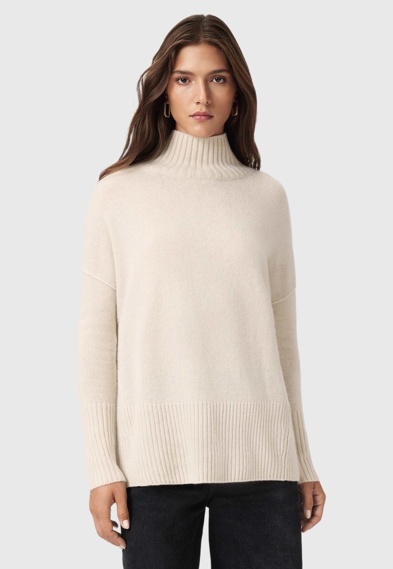 Kremowy sweter z wysokim kołnierzem, o prążkowanej fakturze, w luźnym kroju i długich rękawach. Wykończony prążkowanym dołem dla dodatkowego akcentu.