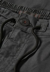 Grå tygshorts med elastisk midje, som har en rund svart knapp och en dragsko. Materialet har en texturerad yta.