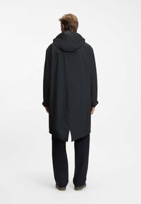 Cappotto lungo nero con cappuccio, realizzato in materiale impermeabile, presenta un orlo asimmetrico e polsini con bottoni. Design semplice e funzionale.