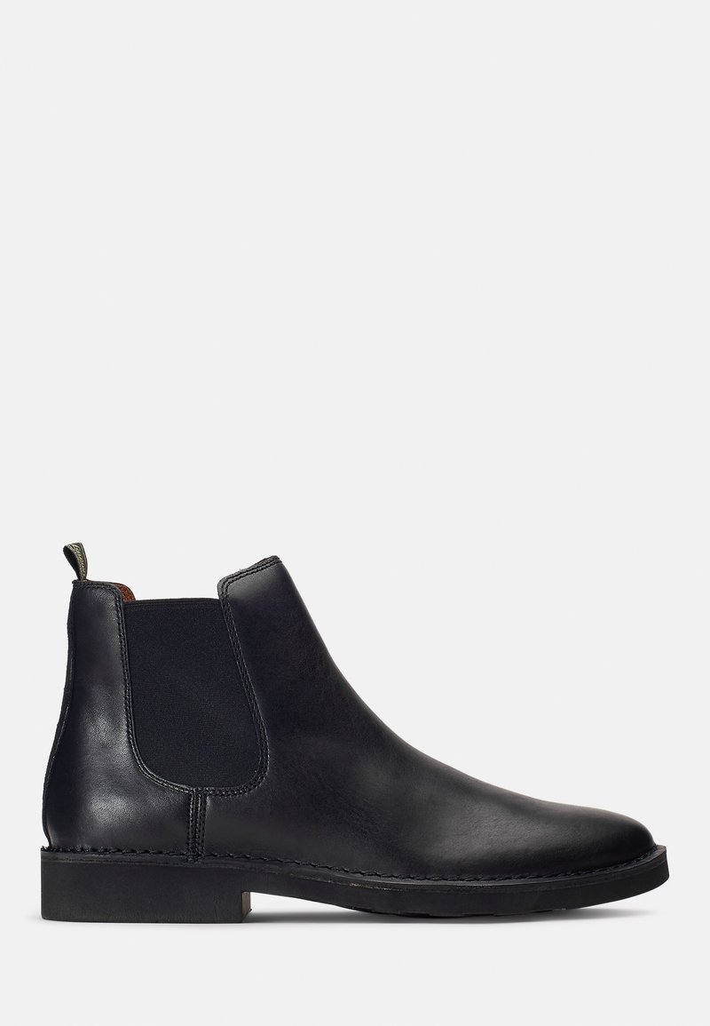 Botas Chelsea de cuero negro con paneles elásticos laterales, textura suave, punta redondeada y suela plana de goma, que incluyen una pequeña tira para tirar.