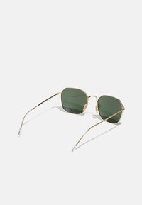 Ochelari de soare cu ramă aurie, lentile cu nuanță verde, formă octogonală, brațe subțiri din metal și vârfuri din silicon transparent pentru confort.