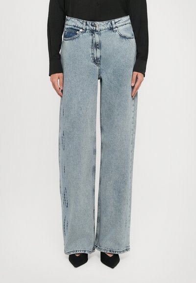 Jean large bleu clair avec des détails déchirés et des poches avant, fabriqué en denim. Fini avec une fermeture à bouton classique et une fermeture éclair.