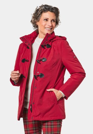 Red, waterproof parka jacket with a hood, featuring toggle fasteners, side pockets, and a textured gray sweater underneath.