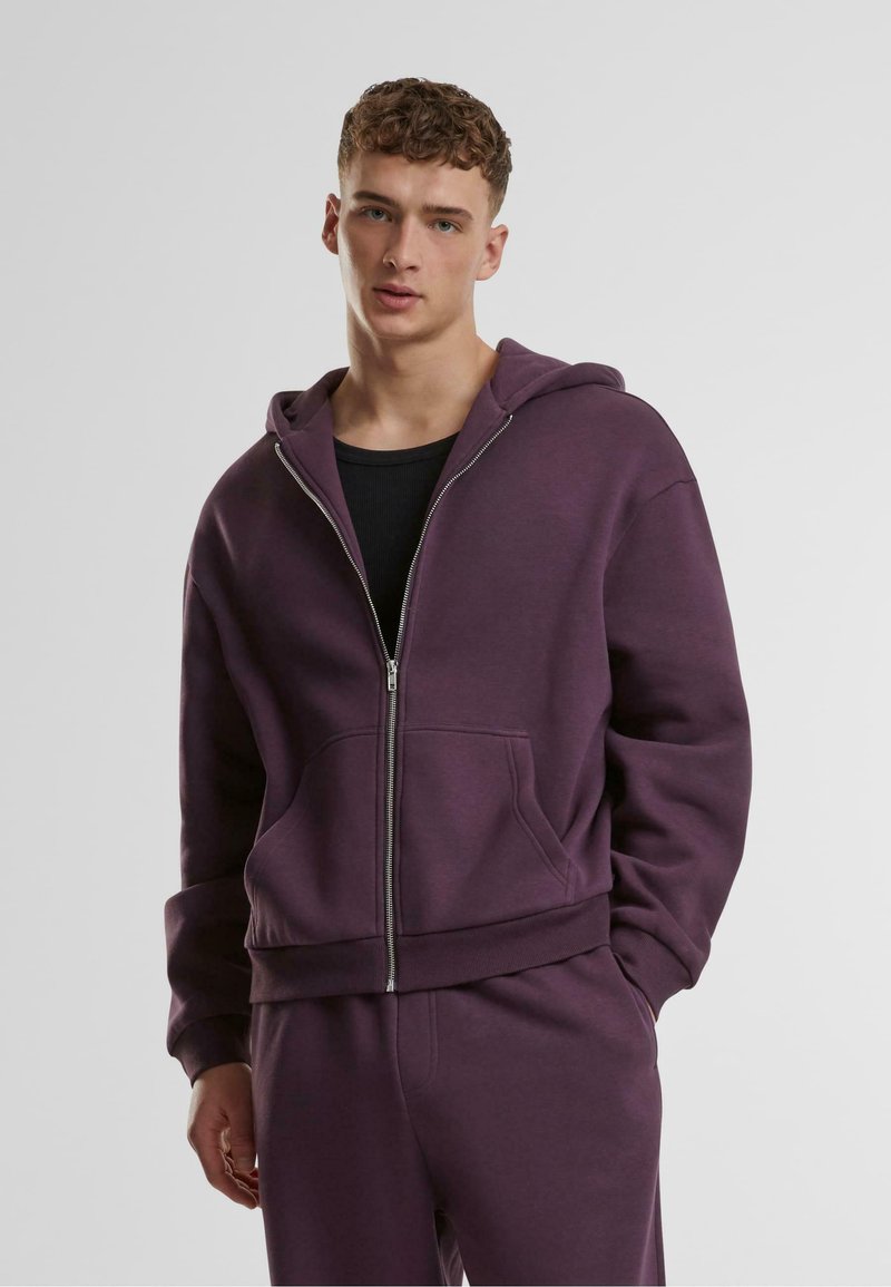 Lilla zip-up hettegenser med snøring i hetta, ribbestrikkede mansjetter og frontlommer. Kombinert med matchende bukser laget av et mykt stoff.