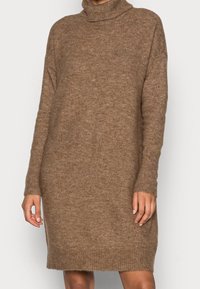 Brun stickad klänning med hög krage, långa ärmar och ribbade åtlar. Mjukt material och avslappnad passform, som når till mitten av låret.