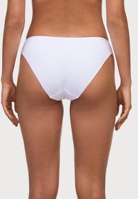 Bas de bikini blanc avec une texture lisse, un design taille basse et une couverture minimale. Présente des lignes épurées et une finition sans couture.