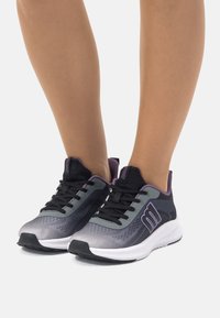 Zapatillas deportivas negras y grises con acentos morados, parte superior de malla, diseño texturizado y suela de goma, con cierre de cordones y detalle de logo.