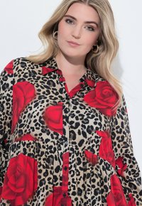 Camicia con stampa leopardata e rosa rossa, con colletto, chiusura a bottoni, maniche lunghe e un design svasato realizzata in tessuto leggero.