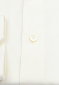 Witte shirtstof met een fijne diagonale weving. Voorzien van een enkele parelknop en een net gevouwen manchet. Minimalistisch ontwerp.