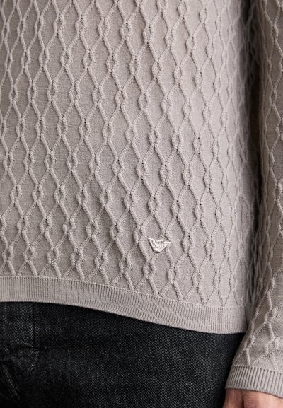 Gai pelēks adīts džemperis ar teksturētu dimanta rakstu, ribotām piedurknēm un apakšmalu, ar mazu izšūtu logotipu uz priekšpuses.