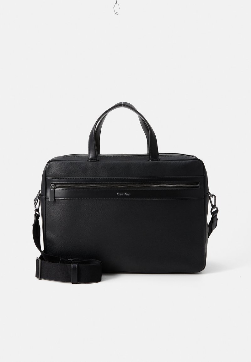Sac d'ordinateur portable noir avec deux poignées, une bandoulière réglable, une poche frontale zippée et un matériau texturé lisse. Design rectangulaire.