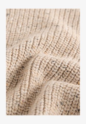 Material bej texturat cu un model nervurat. Materialul pare moale, cu pete subtile de nuanțe mai închise pe tot parcursul. Aspect moale și natural.