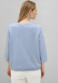 Sweatshirt en mélange de coton bleu clair avec des manches trois-quarts et un col rond. Texture lisse, col et ourlet à finition côtelée.