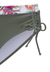 Groene bikini onderkant met een bloemenpatroon op de tailleband, voorzien van gathered details en een strikaccent aan de zijkant. Gladde stoftextuur.