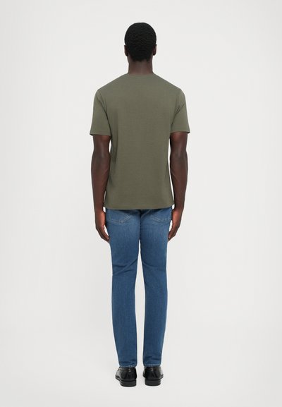 Tricou scurt cu mânecă, de culoare verde khaki, cu guler rotund, de formă ajustată. Asortat cu blugi din denim albastru și pantofi negri. Design simplu, fără modele.