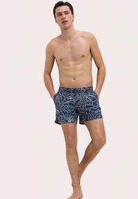 Badbyxor i mörkblått med vitt konturmönster. Elastisk midjeresår, sidofickor, längd ovanför knäna, tillverkade av lättviktigt material.