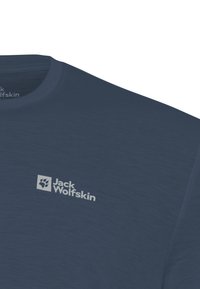 T-shirt bleu marine à col ras du cou avec un logo Jack Wolfskin gris clair représentant une empreinte de patte sur le côté gauche de la poitrine.