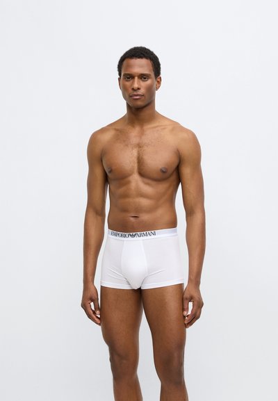 Boxer da uomo bianchi in cotone con fascia elastica bianca con il marchio "EMPORIO ARMANI" in lettere nere. Design semplice, vestibilità aderente.
