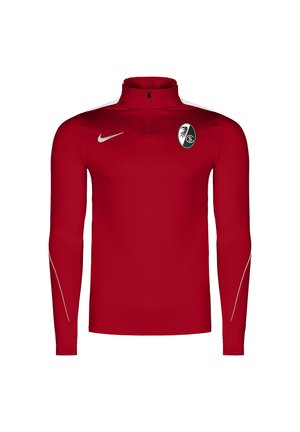 Rød sports top med lange ærmer og kvart lynlås, hvid Nike-logo på højre bryst og sort-hvid klubemblem på venstre bryst.
