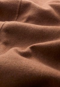 Brown wool fabric with a soft, textured surface, featuring gentle folds and a muted, warm hue. No visible patterns or hardware details.