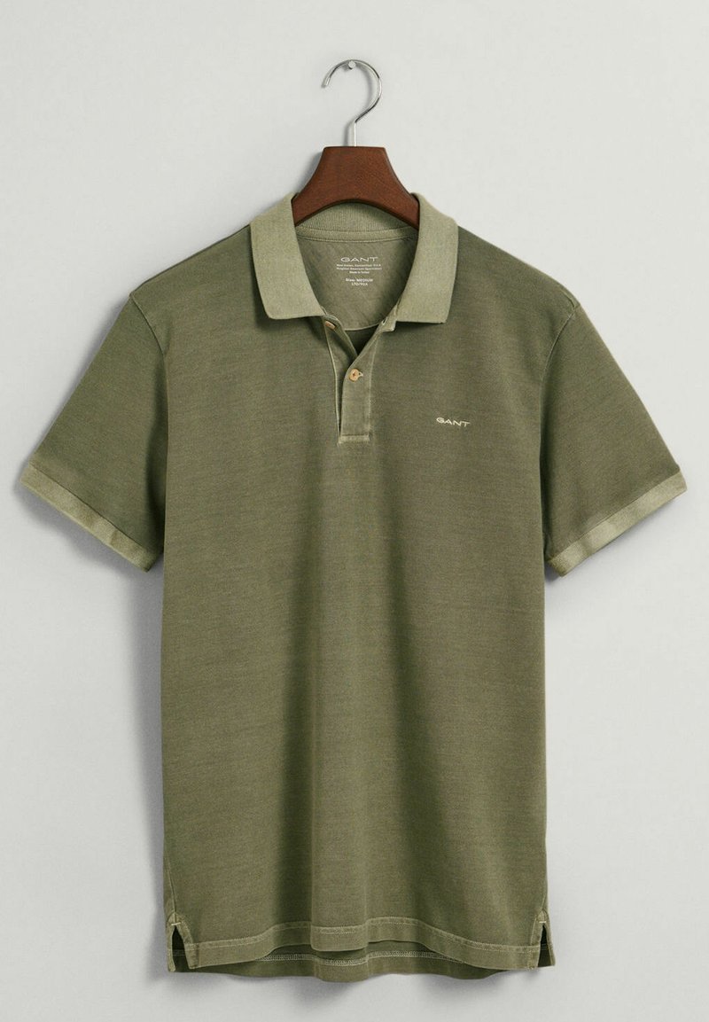 Polo olive en coton, doté d'un col, d'une patte de boutonnage à deux boutons et d'éventails sur les côtés. Logo brodé sur la poitrine.