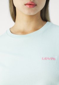 Vaaleansininen lyhythihainen t-paita puuvillaa, jossa pyöreä pääntie. Vasemmassa rinnassa valkoinen ja vaaleanpunainen brodeerattu Levi's-logo.