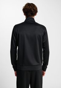 Sort atletisk jakke lavet af glat, let materiale. Den har en stålkrave og ribbede manchetter, designet til en tæt pasform.