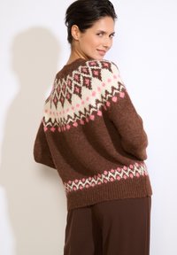Hnedý pletený sveter s geometrickým vzorom v krémovej, ružovej a hnedej farbe na ramenách a spodnom okraji; mäkká, textúrovaná tkanina.