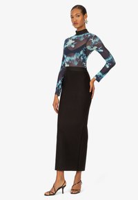 Langärmliges Oberteil mit blauem Blumenmuster, schwarzer High-Waist-Rock und schwarzen Riemchen-Heels. Durchsichtiges Material und taillierte Silhouette mit schlankem Design.