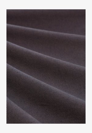 Krupan plan tamne tkanine s finom, gusto tkanom teksturom i mekim naborima koji stvaraju dijagonalne linije preko površine.