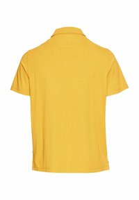Żółta koszulka polo z teksturowanej tkaniny, krótkie rękawy i klasyczny kołnierzyk. Posiada boczne rozcięcia, co ułatwia ruch.