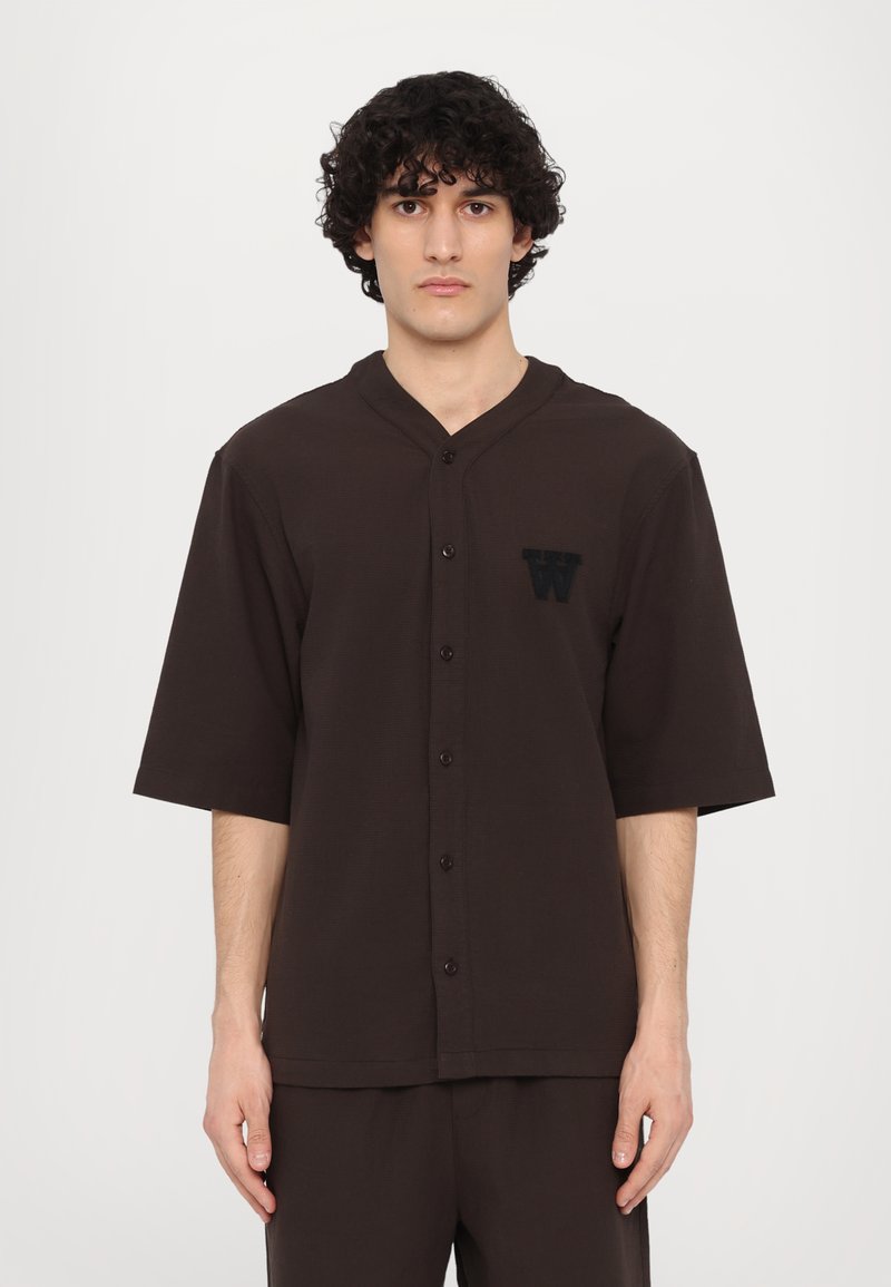 Brown short-sleeve button-up shirt with a v-neck, featuring a textured fabric and an embroidered letter "W" on the left chest.