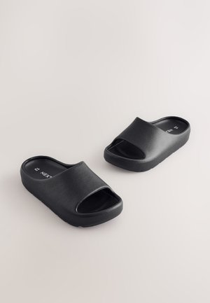 Sorte slidesandal med bred rem, åben tå-design, tekstureret syntetisk overdel og en polstret sål. Flad, minimalistisk profil.