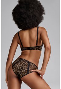 Souprava prádla v leopardím vzoru se průhlednou tkaninou, černými popruhy a kontrastním lemováním. Design obsahuje podprsenku a spodní část ve stylu hipster.