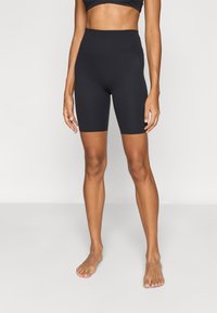 Μαύρο αθλητικό σορτς από ελαστικό ύφασμα, με ψηλή μέση και εφαρμοστή σχεδίαση που φτάνει μέχρι το μέσο του μηρού.