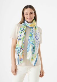 Foulard en tissu léger à motif floral coloré, présentant des teintes de bleu, vert, orange et jaune, avec des bords frangés et des accents en denim.