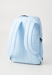 Lichtblauwe rugzak met gevoerde rug en schouderbanden, met een mesh-structuur en ritssluiting. Eenvoudig, functioneel ontwerp met een slanke uitstraling.