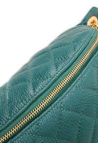 Gewatteerde groene leren tas met een gouden rits. Het oppervlak heeft een diamantpatroon en een gladde textuur, met details die het vakmanschap benadrukken.