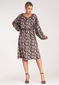 Kwiatowa sukienka z długimi, zwiewnymi rękawami, wcięciem w talii, o długości do kolan, na czarnym tle, z różowymi i białymi kwiatami. Gładki, lekki materiał.