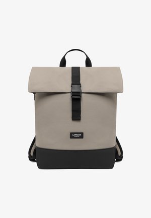 Sac à dos en tissu gris avec un rabat supérieur, fermeture par sangle noire et base noire. Comprend une poignée supérieure et des bretelles rembourrées en mesh.