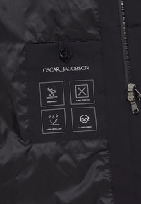 Sort jakke med stof, der har et logo og symboler, der indikerer vindafvisende, 4-vejs stræk, vandafvisende og 3-lags stof. Med lynlåsdetaill.