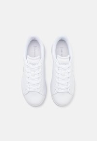 Vita sneakers gjorda av slät syntetiskt material med rund tå, platta snörningar och präglad logotyp på plösen och hälen. Minimalistisk design.