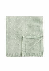 Couverture en tricot vert clair avec un motif de points texturé, présentant des bords côtelés et un coin replié pour plus de détails.
