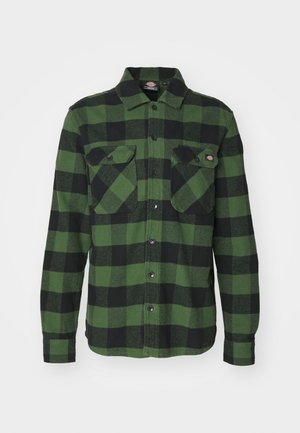 Zöld és fekete kockás flanel ing, két mellzsebbel, gombos elülső résszel, hosszú ujjakkal és hegyes gallérral. Puha tapintású.