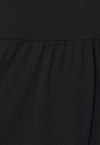 Tissu noir texturé avec un design froncé en bas, créant des drapés doux. Matériau lisse et extensible avec une finition douce.