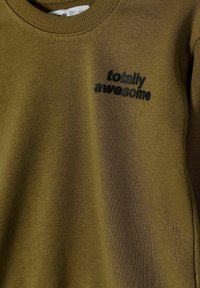 Olijfgroen sweatshirt met geribbelde ronde hals, met geborduurde tekst "totally awesome" in zwart. Zachte textuur en casual pasvorm.
