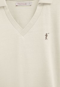 Cream-colored V-neck Polo Club sweater with small embroidered logo of a person holding a golf club on the left chest.